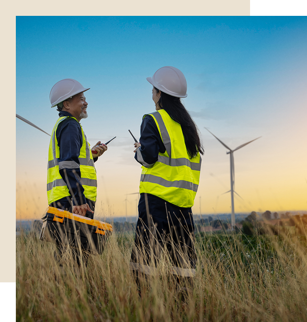 Two workers discussing near wind turbines.